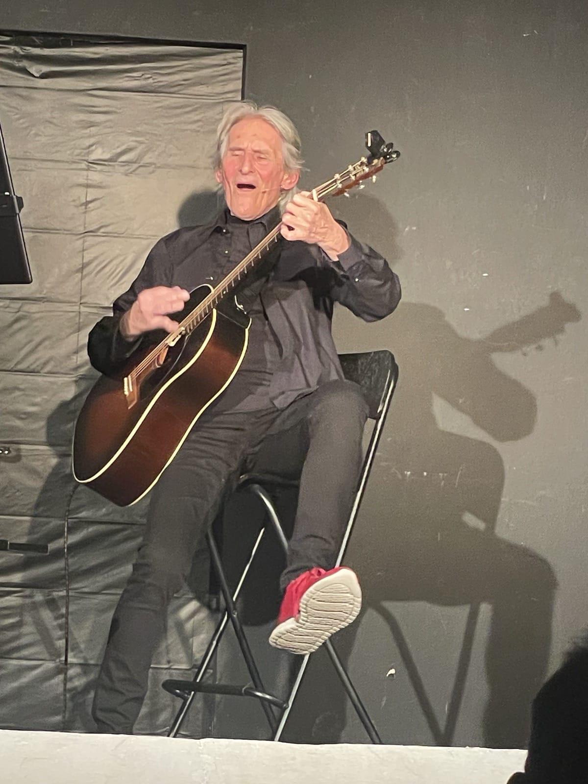 Franz Sobotka lachend auf der Bühne mit Gitarre